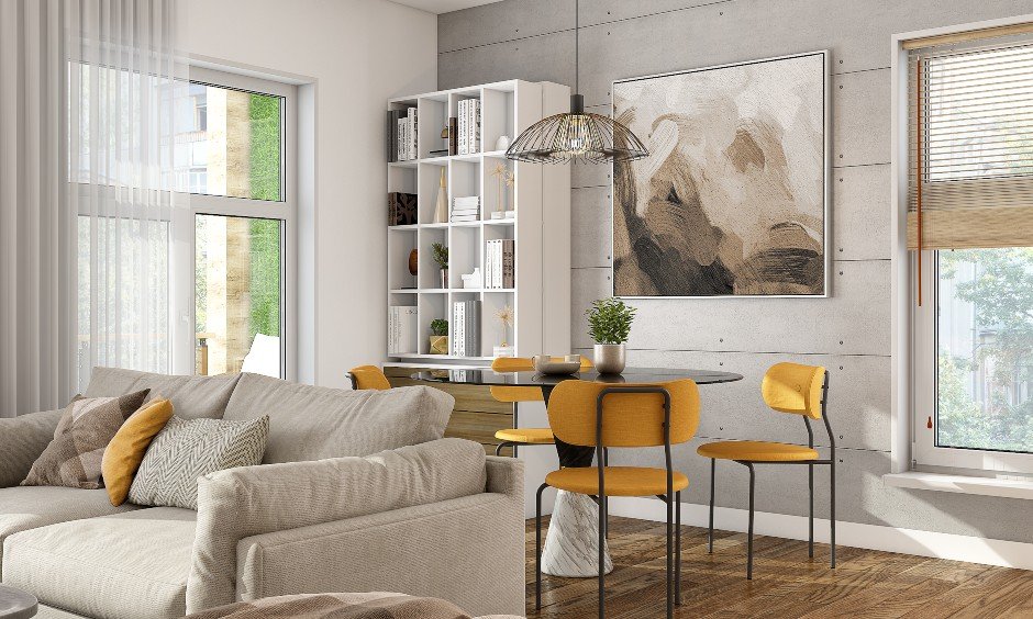 1 bhk interior dining room design with glass top table, four yellow cushioned chairs and bookshelf lends a sleek look.