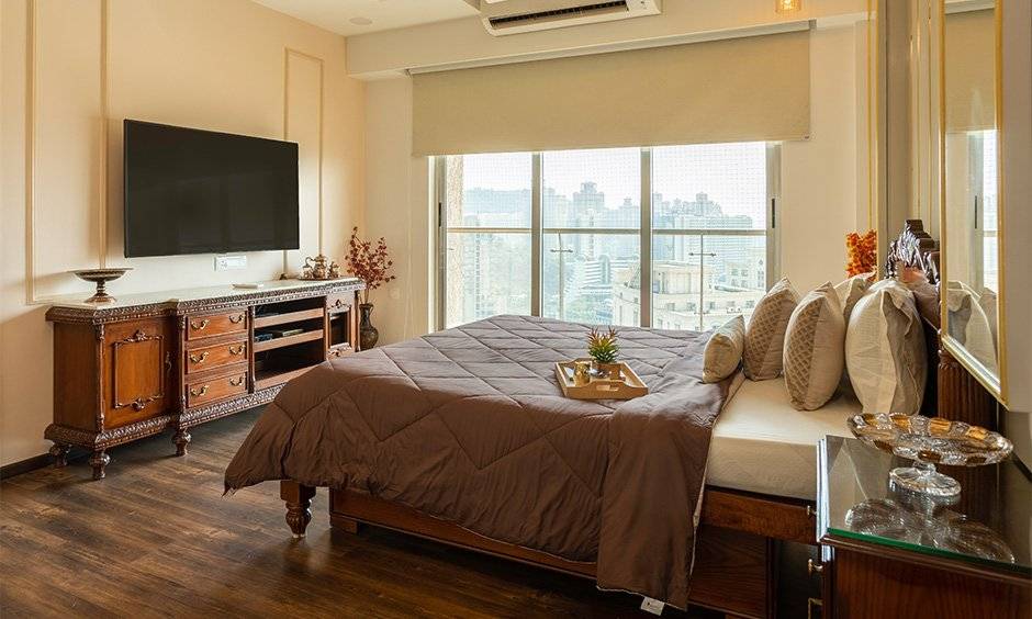 The second bedroom depicts a traditional royal design with a carved wooden TV designed by low budget interior designers in mumbai